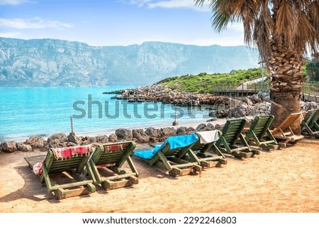 Stones on the shore and wooden deck chairs on Cleopatra Island, Aegean Sea, Marmaris, Turkey
