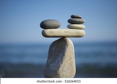 Stones pile background. Scales balance. Balanced stones on the top of boulder. To weight pros and cons. Balance of stones on a blue sky background with a copy space. - Shutterstock ID 526264015