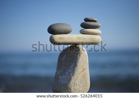 Stones pile background. Scales balance. Balanced stones on the top of boulder. To weight pros and cons. Balance of stones on a blue sky background with a copy space.
