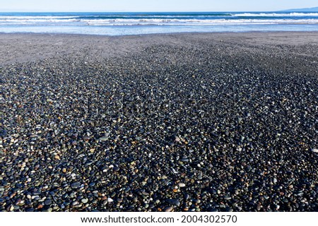 Stones and possibly gems, cover the shore at Gem Stone Beach, Western Southland, New Zealand