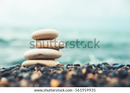 Stones pyramid on pebble beach symbolizing stability, zen, harmony, balance. Shallow depth of field.