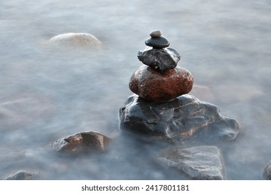 Stones pyramid on water symbolizing zen, harmony, balance. Ocean in the background - Powered by Shutterstock