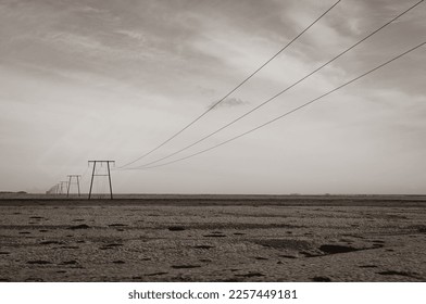 stony desert in Iceland - a striking black and white portrayal of man's impact on the rugged terrain. The powerlines serve as a symbol of progress amidst the unchanging landscape. - Shutterstock ID 2257449181