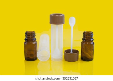 Stool Sample Cup And Medication In Brown Glass Container On Yellow Background