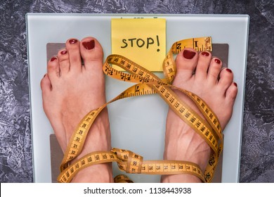 Stop Anorexia Nervosa! Society Perception, Pressure About Weight Problem. Skinny Female Feet On A Scale With Yellow Measuring Tape. Loss Weight Social Stigma. Body  Positive Concept.                