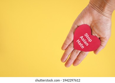 
Stop Asian Hate , White Message, On Red Heart Paper In Hand With Yellow Background And Copy Space , Anti Racist ,hate Crimes Against Asians Concept