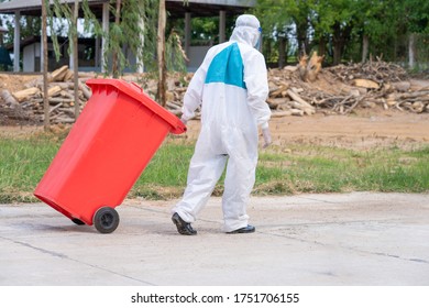 Stop Biohazard,Garbage Men In Coronavirus Hazmats Working Together On Emptying Dustbins For Trash Removal With Truck Loading Waste And Trash Bin.