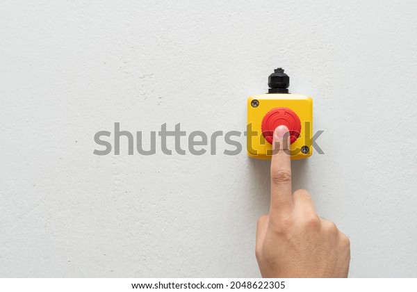 Stop Button and the Hand of Worker About to\
Press it. emergency stop button. Big Red emergency button or stop\
button for manual\
pressing.