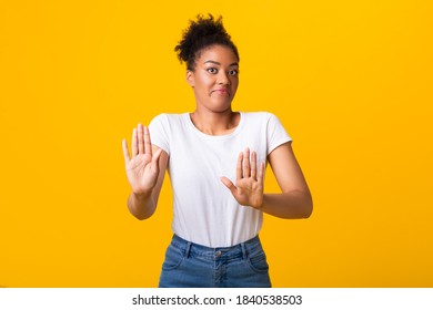 Stop Concept, Thank You But No. Portrait of black lady making stop hand gesture, isolated on yellow studio background. Displeased woman in fear showing denial sign with two palms to camera