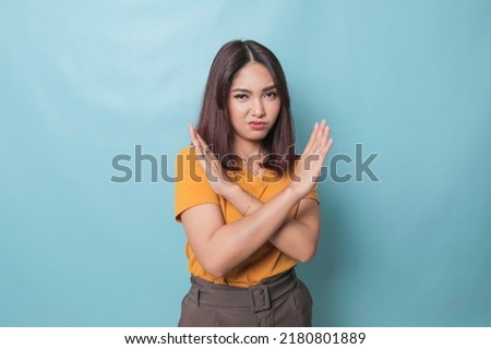 Stop. Concerned Asian woman showing refusal sign, saying no, raise awareness, standing over blue background