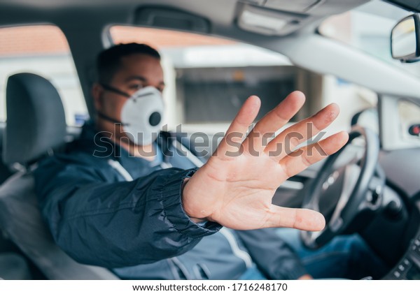 stop corona. quarantine.  covid 19. coronavirus.\
hand of young hispanic man, a driver of car in a protective mask.\
prevent  spread of coronavirus. young hispanic taxi driver stops\
pandemia