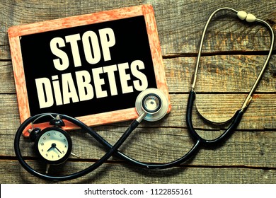 STOP DIABETES CONCEPT. STOP DIABETES handwritten with white chalk on a blackboard on wood background