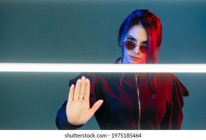 Stop Discrimination. Neon Light Portrait. Feminist Empowerment. Strict Woman In Sunglasses In Red Blue Glow With White LED Warning With Nope Gesture Isolated On Blue Copy Space.