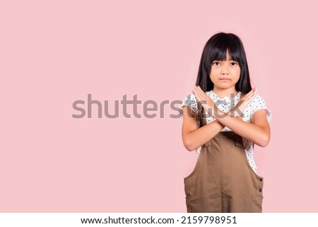 Stop gesture. Asian little kid 10 years old showing two hands cross arms say no X sign at studio shot isolated on pink background, Happy child girl disagreement opposition