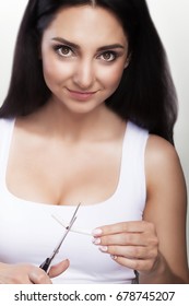 Stop Growing. Portrait Of A Beautiful Smiling Woman Holding Cigarettes And Scissors In Her Hands. The Concept Of Purchasing Cigarettes. On A Gray Background.