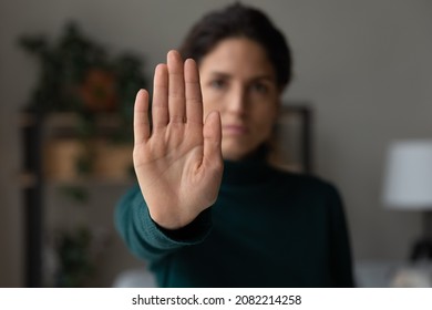 Stop it. Strong serious young lady extending hand forward forbidding saying no to harassment bullying abuse violence against women. Focus on female palm demonstrating gesture of rejection prohibition