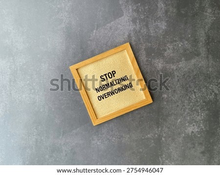 Stop normalizing overworking message in wooden frame representing work life balance concept.