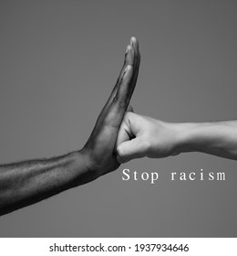 Stop racism. African and caucasian hands gesturing on gray studio background. Tolerance and equality, unity, support, kindly coexistence together concept. Worldwide multiracial community.