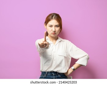 Stop right her. Silly asian girl pulling index finger forward in stop or prohibition motion, shake forefinger telling no way, rejecting or deny something, frowning disappointed, dont give permission. - Shutterstock ID 2140425203