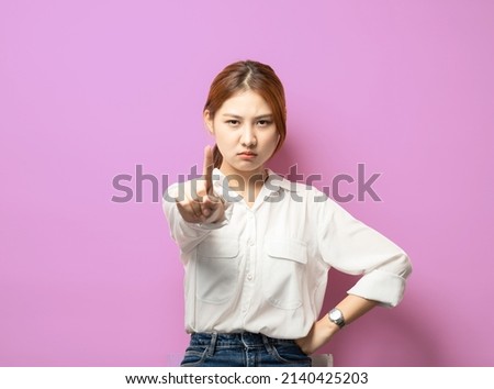 Stop right her. Silly asian girl pulling index finger forward in stop or prohibition motion, shake forefinger telling no way, rejecting or deny something, frowning disappointed, dont give permission.