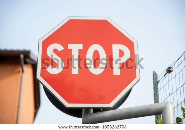 stop road\
sign with low houses and sky\
background