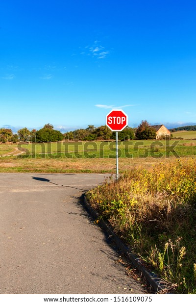 Stop road\
sign at rural intersection. Transport safety. Environment. Warning\
symbol. Obligation to stop the\
vehicle.
