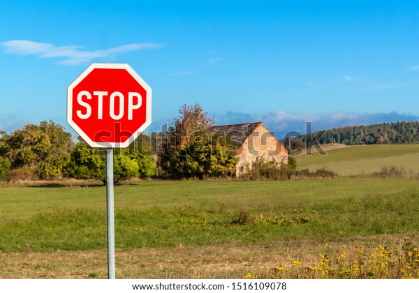 Stop road
sign at rural intersection. Transport safety. Environment. Warning
symbol. Obligation to stop the
vehicle.