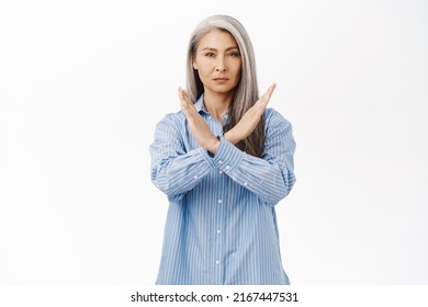 Stop. Serious Asian Woman Showing Prohibit, Forbid Gesture, Extending Palms Forward And Saying No, Step Back, Standing Over White Background