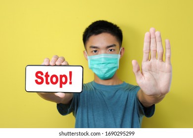 Stop Share Incorrect News About Pandemic Coronavirus, Young Asian Man Doing Stop Gesture To Share Hoax Of Coronavirus, Isolated On Yellow
