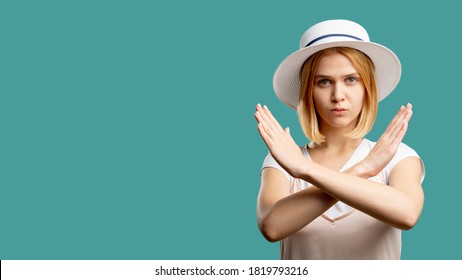 Stop Sign. Forbidden Gesture. Serious Woman In White Crossing Hands Looking At Camera Isolated On Green Copy Space. Wrong Way. No Entrance. Disapproval Emotion. Advertising Background