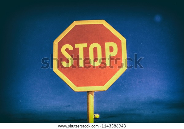 Stop sign in the night city.\
Traffic regulation. Blue sky. Analog photo filter with\
scratches.