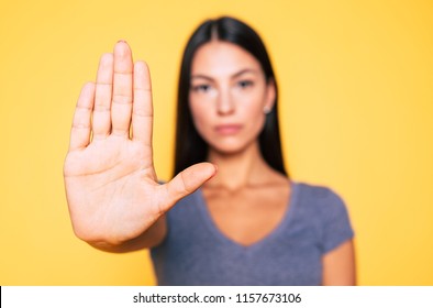 Stop Sign, Palm, Hand On Camera, Symbol - Don't Move. Close Up Photo Of Young Serious Woman Shows Her Palm Right On Camera Isolated On Yellow Background