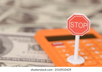 The stop sign placed atop a calculator symbolizes the importance of financial prudence and the need to halt impulsive spending or risky investments.