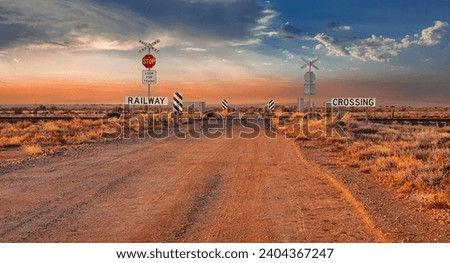 Stop sign at a railway crossing in the outback of South Australia. sign saying look out for trains. Sunrise