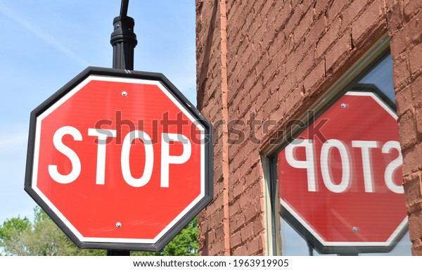 Stop sign with a reflection of the sign mirrored\
in a window