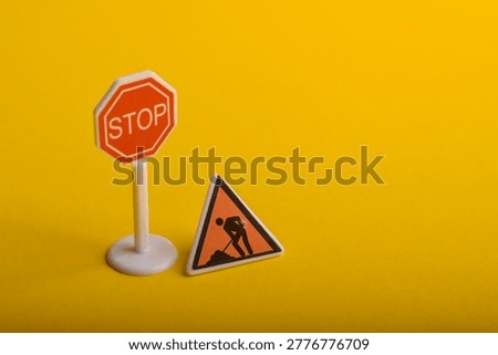 Stop sign and road work warning symbol on yellow background representing traffic control, caution, construction alert, and safety awareness in transportation.