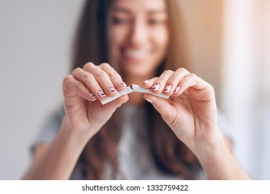 Stop smoking cigarettes concept. Close up of young smiling girl holds broken cigarette in hands. Happy female quitting smoking cigarettes. Quit bad habit, health care concept. No smoking. Tonned. - Shutterstock ID 1332759422