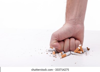 Stop Smoking. Close Up Of Male Hand Breaking Cigarettes With His Fist. Isolated And Copy Space In Left Side