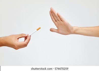 Stop Smoking Concept. Closeup Of Woman Hand Refusing To Take Cigarette. Human Hand Holding Cigarette On White Background. Quit Smoking Concept. High Resolution