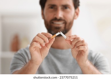 Dejar de fumar. Hombre rompe cigarrillos con fondo borroso, enfoque selectivo