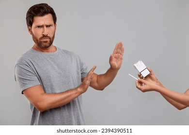 Stop smoking concept. Man refusing cigarettes on grey background