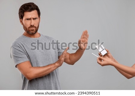 Stop smoking concept. Man refusing cigarettes on grey background