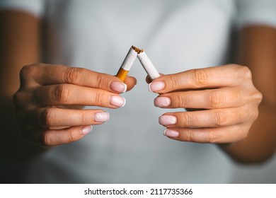 Stop smoking, quit smoking or no smoking cigarettes. Woman holding broken cigarette in hands. Woman refusing cigarettes. Quit bad habit.