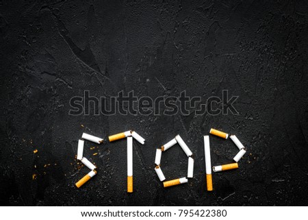 Stop smoking. Word stop lined cigarettes on black background top view copy space
