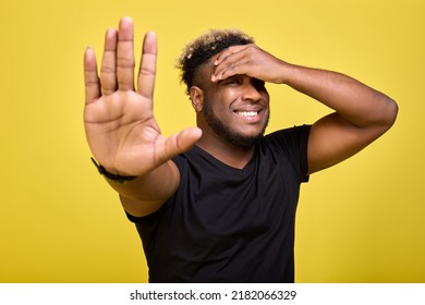 Stop Talking Nonsense - Thinks African American Man In T-shirt On Yellow Background. An African Man Holds His Head And Shows Gesture With Palm Of His Hand So That He Does Not Get Too Close To Him. 