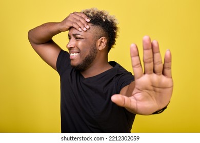 Stop Talking Nonsense - Thinks African American Man In T-shirt On Yellow Background. An African Man Holds His Head And Shows Gesture With Palm Of His Hand So That He Does Not Get Too Close To Him. 