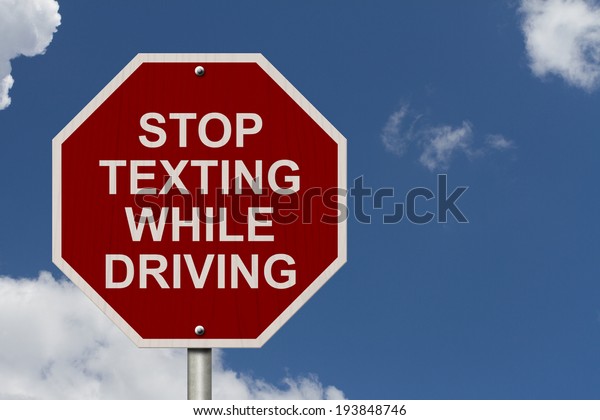 Stop\
Texting While Driving Sign, Red and White Stop sign with words Stop\
Texting While Driving with a blue sky\
background