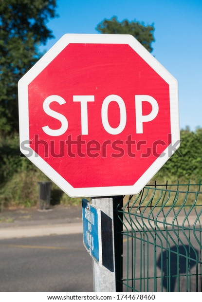 Stop traffic\
sign close up at a road intersection. English language. Beautiful\
colorful surroundings.\
Vertical.