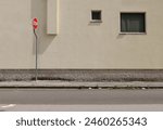 Stop traffic sign on concrete sidewalk. Pale yellow plaster facade with windows on behind,  urban street in front. Background for copy space.