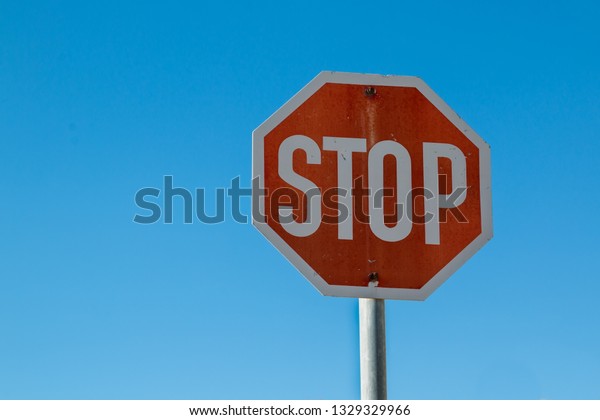 Stop traffic sign with a part of the pole.\
Bright blue sky in the\
background.